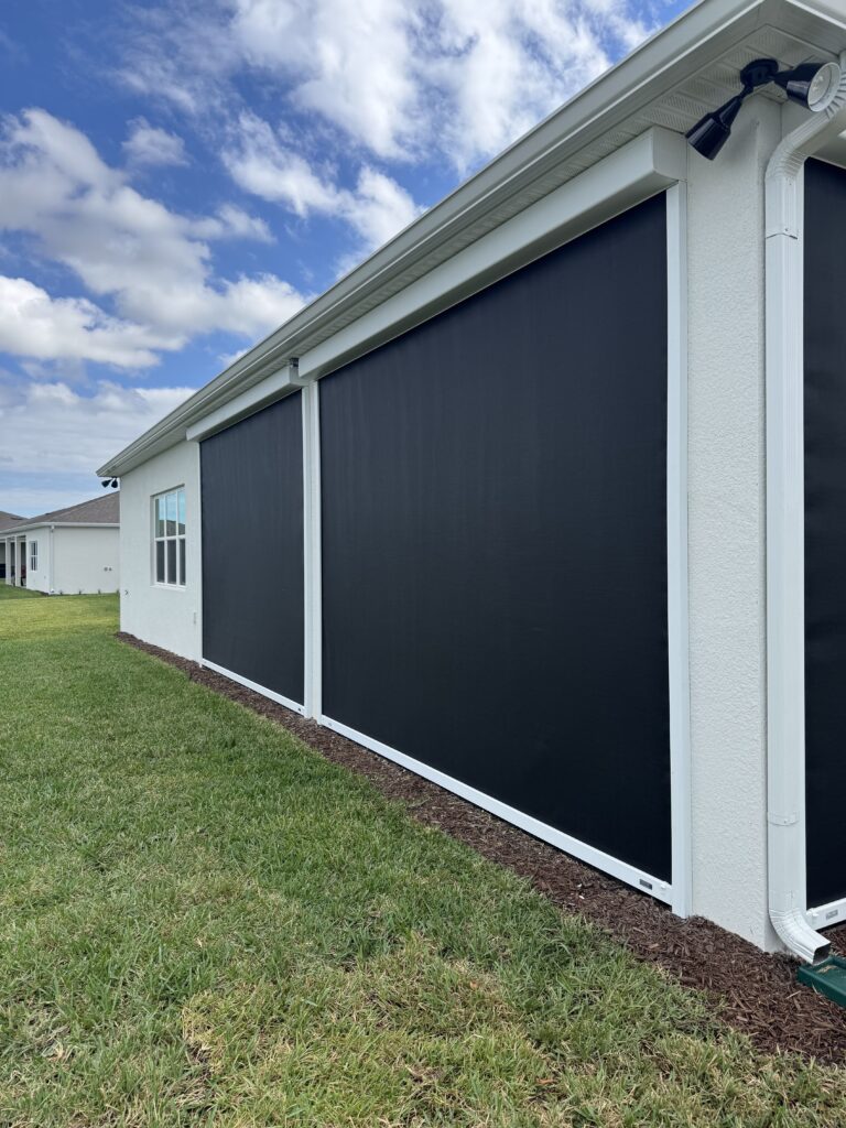 Black MagnaTrack Defender motorized hurricane screen installed on a lanai in Del Webb, Viera, Florida, providing privacy, shade, and storm protection.
