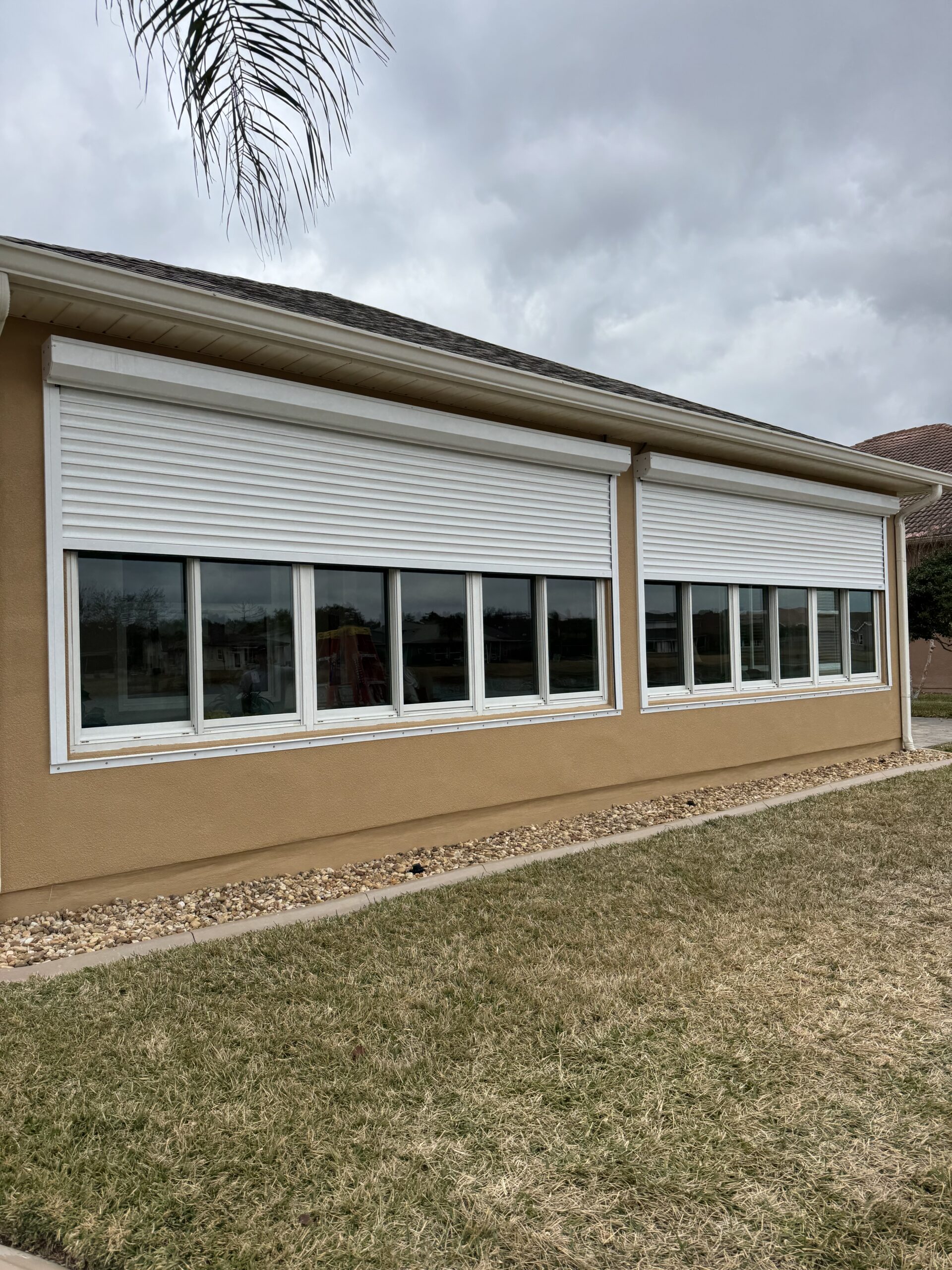 Custom roll metal hurricane shutters installed over large residential windows in Titusville FL by Affordable Glass Protection